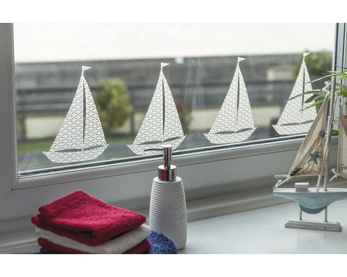 Dekoratives Fenster mit Segelboot-Motiv, ergänzt durch Handtücher und einen Seifenspender