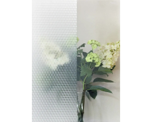 Strukturglas mit dreieckigem Muster neben einer Vase mit Blumen