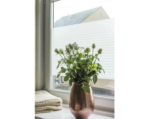 Bouquet dans un vase sur un rebord de fenêtre devant un store plissé