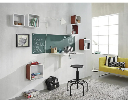 Wohnraum mit Wandregalen, Schreibtisch, Tafel, Hocker und Sofa