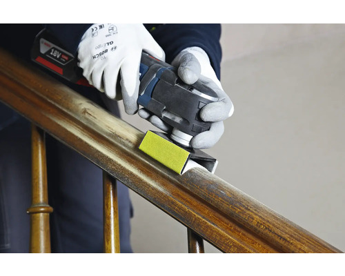 Eine Person verwendet ein Multitool zum Schleifen eines Holzgeländers.