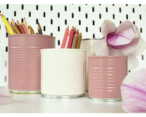 Dekorative Stifthalter aus bemalten Konservendosen mit Buntstiften und einer Magnolienblüte.