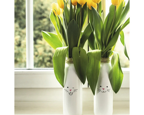 Zwei Vasen mit Hasenmotiven und gelben Tulpen auf einem Fensterbrett.