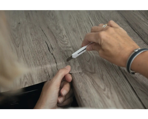 Coupe d''une dalle de sol en vinyle avec un cutter