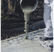 Du béton est coulé sur des pavés
