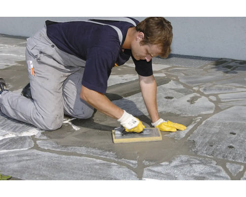Handwerker verfugt Steinplatten mit einem Fugbrett