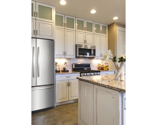 Cuisine claire avec réfrigérateur, micro-ondes et plaque de cuisson en acier inoxydable, ainsi qu''un îlot de cuisine et des armoires hautes