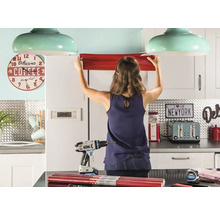 Femme fixant un film pour meubles dans une cuisine avec des outils.