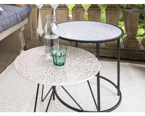 Zwei runde Beistelltische mit Wasserflasche und Glas auf dem Balkon.