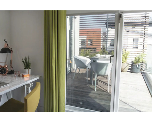 Helles Zimmer mit Schreibtisch, Stuhl und Vorhang, Blick auf eine Terrasse mit Tisch und Stühlen