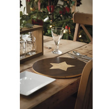 Festlich gedeckter Holztisch mit Teller, Besteck, Glas, Tischset und Weihnachtsbaum im Hintergrund