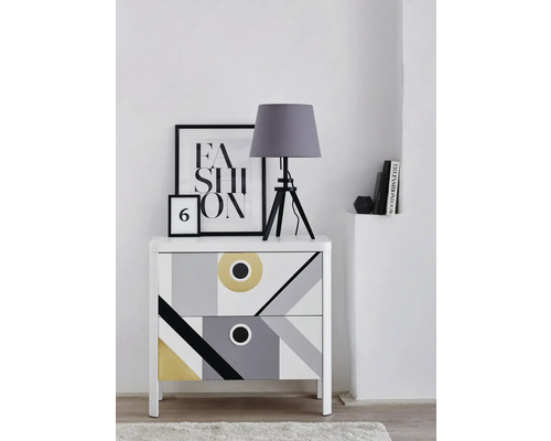 Nachttisch mit geometrischem Muster, Tischlampe und Dekoration auf einer weißen Kommode