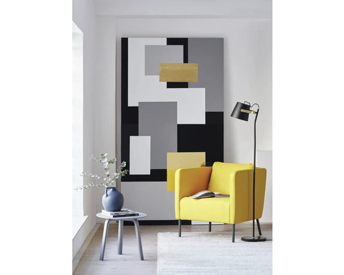Wohnzimmer mit Sessel, Stehlampe, Beistelltisch und abstraktem Wandbild in geometrischem Design.