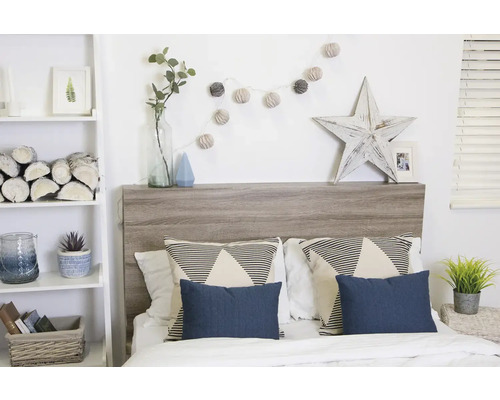 Chambre avec lit, tête de lit en bois, coussins et éléments décoratifs tels qu''une guirlande lumineuse et une étoile en bois