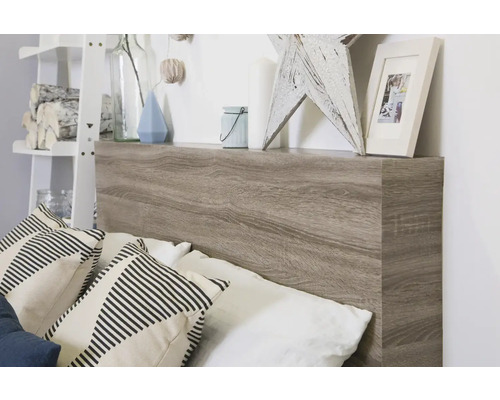 Lit avec tête de lit en aspect bois et étagère avec objets de décoration et coussins