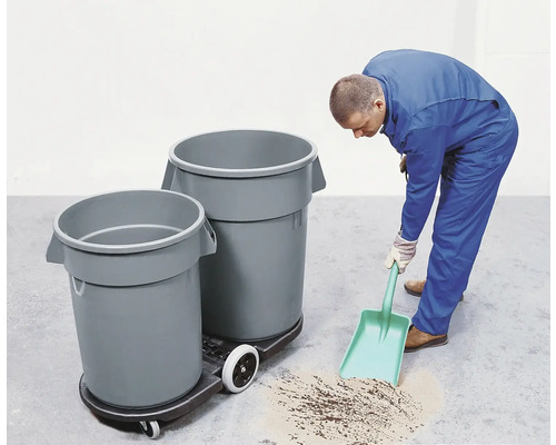 Un homme nettoie le sol avec une pelle à poussière à côté de poubelles sur une planche à roulettes