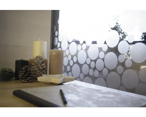 Décoration avec bougies et pommes de pin devant un film de fenêtre