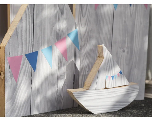 Bateau décoratif en bois devant un mur en bois avec une guirlande de fanions