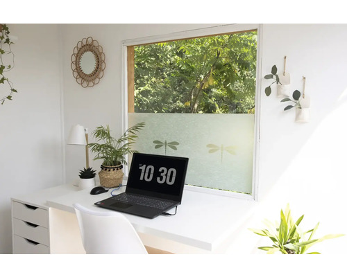 Espace de travail lumineux avec bureau, ordinateur portable et film pour fenêtre avec motifs libellules