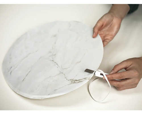 Person schneidet Folie mit Marmormuster mit einem Cuttermesser zu.