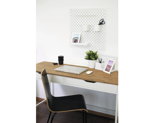 Espace de travail avec bureau, chaise, panneau perforé et fournitures de bureau pour un environnement organisé.