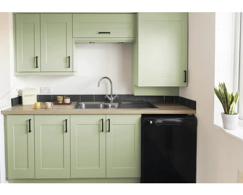 Cuisine lumineuse avec évier, robinet, meubles bas, meubles hauts et un réfrigérateur noir