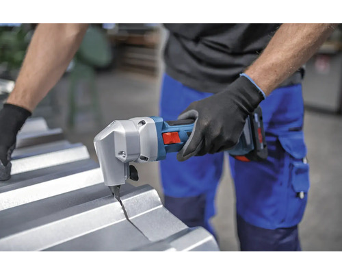 Une personne coupe une tôle avec une cisaille à tôle sans fil