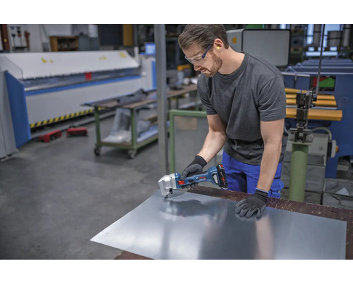 Artisan coupant une tôle métallique avec une grignoteuse sans fil