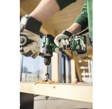 Un artisan perce un trou dans une planche de bois avec une perceuse sans fil.