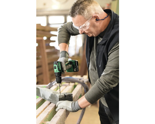 Un homme perce un trou dans une pièce à l''aide d''une perceuse-visseuse sans fil.