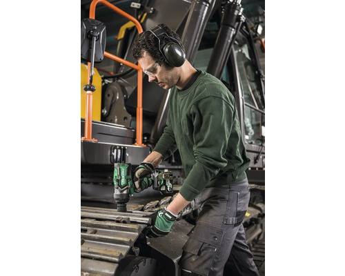 Ein Mann mit Gehörschutz und Schutzbrille benutzt einen Akku-Schlagschrauber an einer Baumaschine.