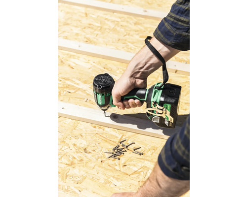 Une personne visse des vis dans du bois à l''aide d''une visseuse à percussion sans fil.