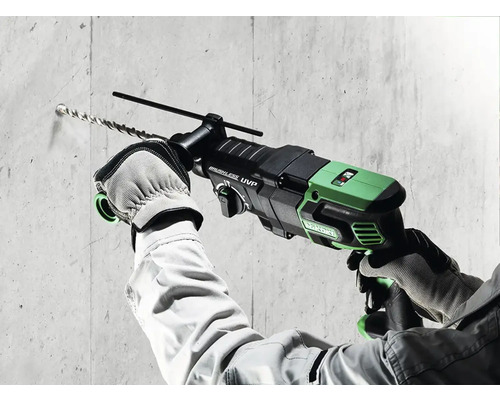 Un homme perce un trou dans un mur en béton avec un perforateur.