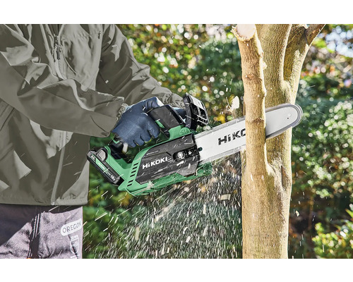 Eine Person benutzt eine Akku-Kettensäge von HiKOKI, um einen Baum zu schneiden.