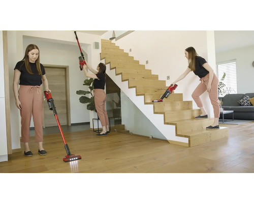 Femme utilisant un aspirateur sans fil dans la maison sur le sol, le plafond et les escaliers