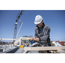 Artisan coupant du bois avec une scie circulaire sur un chantier.