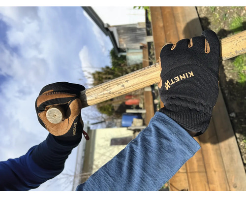 Une personne portant des gants de travail tient un marteau.