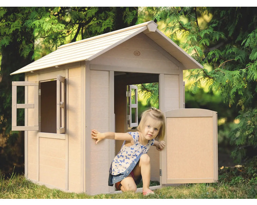 Enfant jouant dans une cabane en plastique dans le jardin.