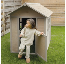 Un enfant sort d''une cabane en bois dans le jardin.