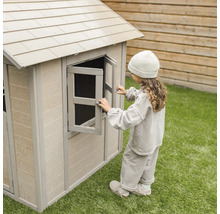 Une fille ouvre la fenêtre d''une cabane en plastique dans le jardin.