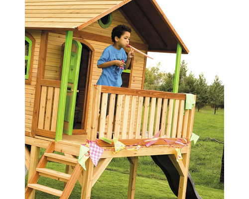 Kind spielt im erhöhten Holzspielhaus mit Rutsche und Veranda im Garten