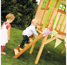Un enfant grimpe à une échelle en bois pour atteindre une cabane de jeu dans le jardin, tandis qu''un autre enfant regarde.