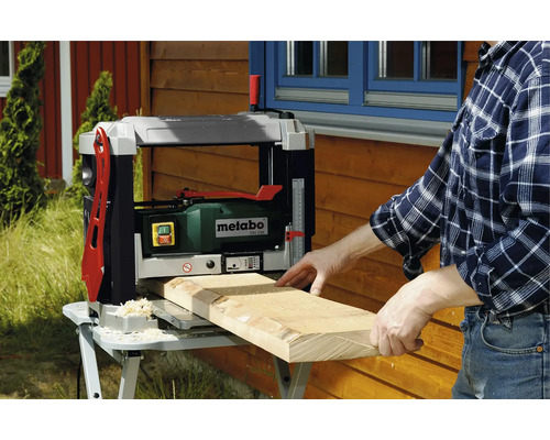 Un homme rabote une planche de bois avec une raboteuse Metabo