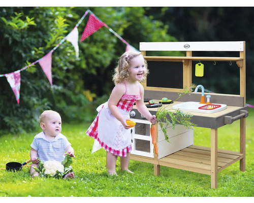 Szene mit Kind an einer Spielküche im Freien mit Tafel, Spüle und Zubehör