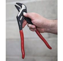 Une main tient une pince multiprise réglable avec une poignée rouge.