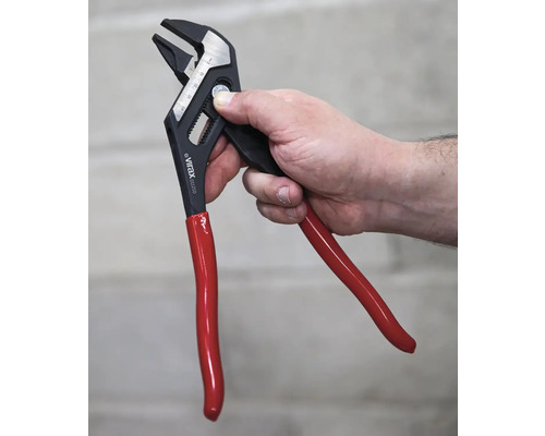 Une main tient une pince multiprise réglable avec une poignée rouge.