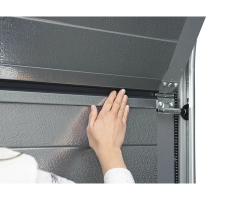 Gros plan d''une porte de garage avec une main vérifiant l''étanchéité