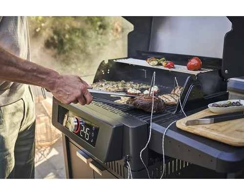 Une personne fait griller de la viande et des légumes sur un gril avec affichage numérique de la température.