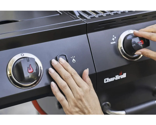 Nahaufnahme eines Char-Broil Grills mit einer Hand, die einen Zündknopf drückt und einen Regler einstellt