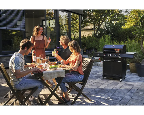 Gruppe von Freunden beim Grillen im Garten mit einem Gasgrill.
